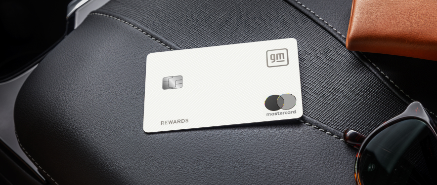 White GM Rewards™ Mastercard® on a vehicle seat beside sunglasses.