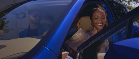 Smiling woman exiting an Opulent Blue Metallic Cadillac LYRIQ after a test drive.