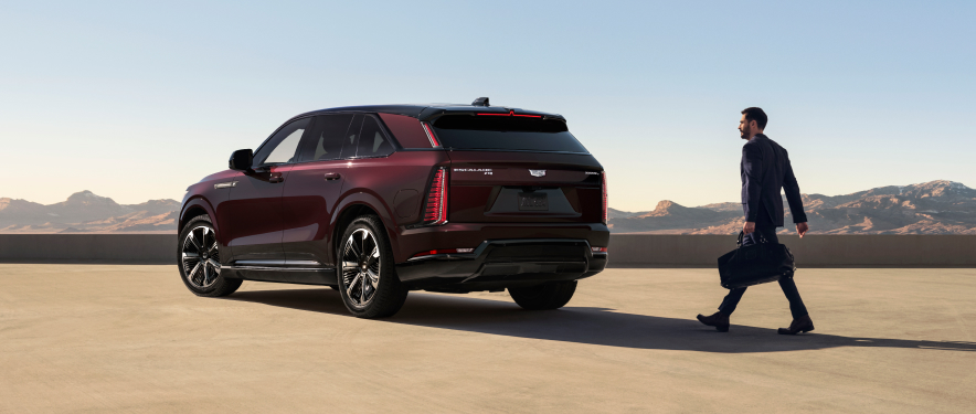 Man walking toward Burgundy Metallic Cadillac Escalade with a bag in his hand.